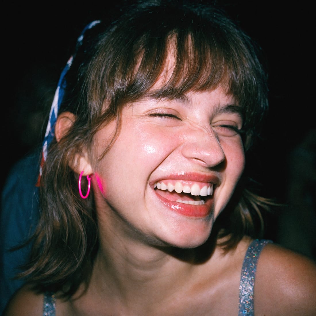 A flash-lit portrait of someone laughing at a party